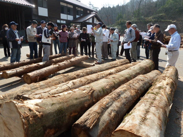 加工場で、古里の森から切り出された木材について説明を聞く人たち